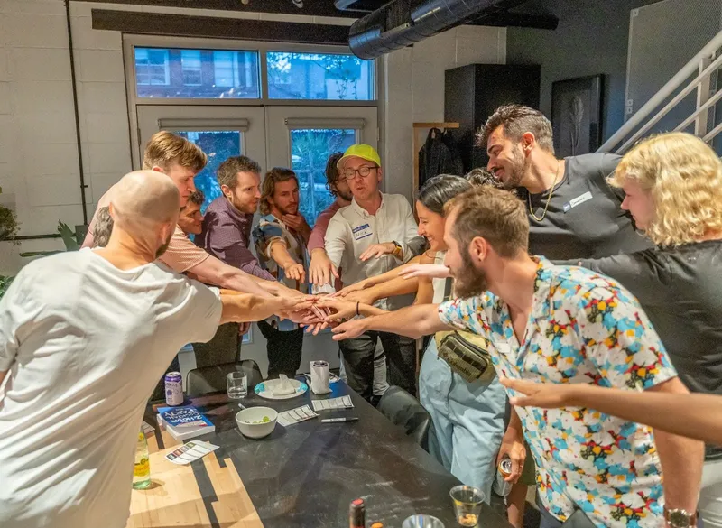 group of people putting their hands on top of each others hands
