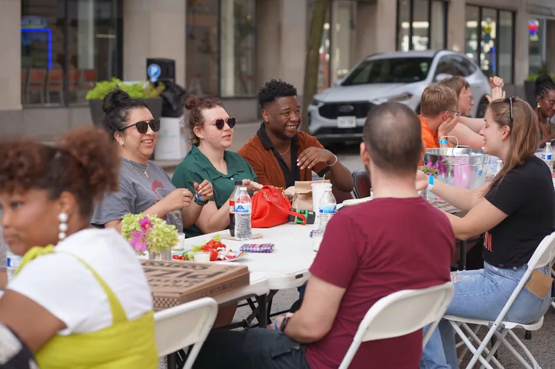 Guests laughing together at the table with a disposable camera sitting in front of them and downtown storefronts behind