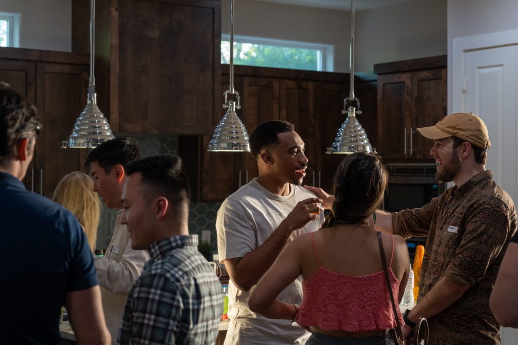 two people laughing, among others, at a party inside someone's home (photo is in the kitchen for a crypto meetup in Texas)