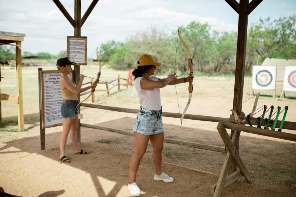 2 women trying archery in adult summer camp