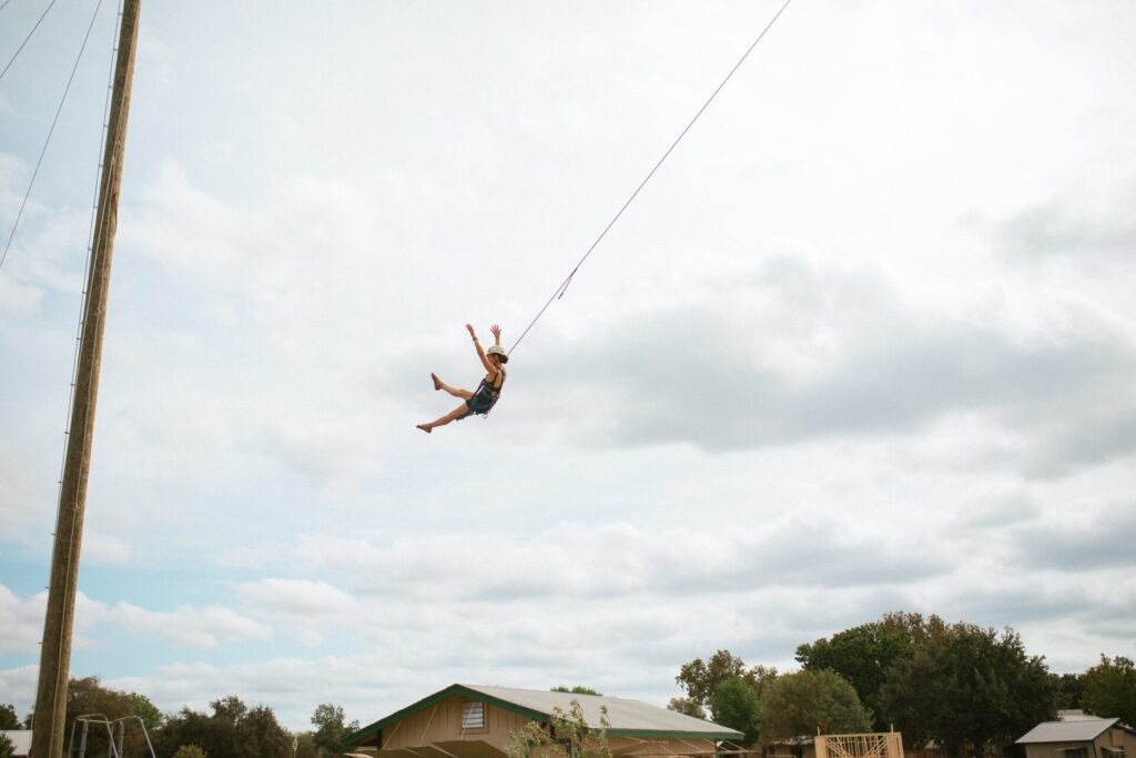 Woman flying with ropes in ropes course in adult summer camp